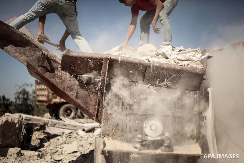 Palestinian laborers work on a crusher machine at a brick factory in center Gaza Strip, Aug 22, 2013. Palestinians re-use old bricks in construction after the Egyptian army started to knock down Gaza smuggling tunnels la...
