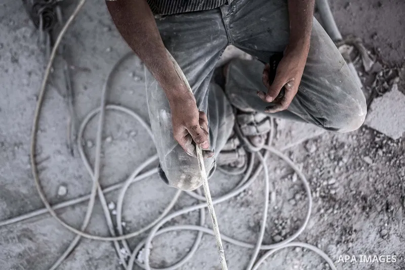 A Palestinian laborer works on a crusher machine at a brick factory in center Gaza Strip, Aug 22, 2013. Palestinians re-use old bricks in construction after the Egyptian army started to knock down Gaza smuggling tunnels...