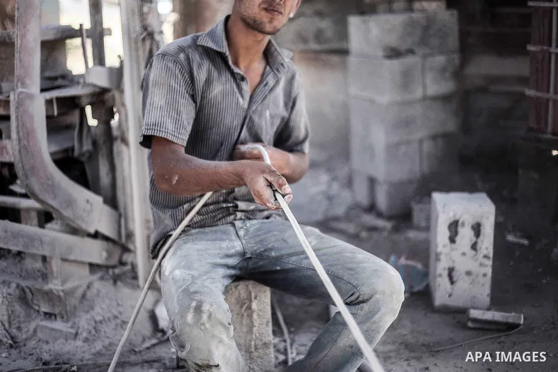 A Palestinian laborer works on a crusher machine at a brick factory in center Gaza Strip, Aug 22, 2013. Palestinians re-use old bricks in construction after the Egyptian army started to knock down Gaza smuggling tunnels...