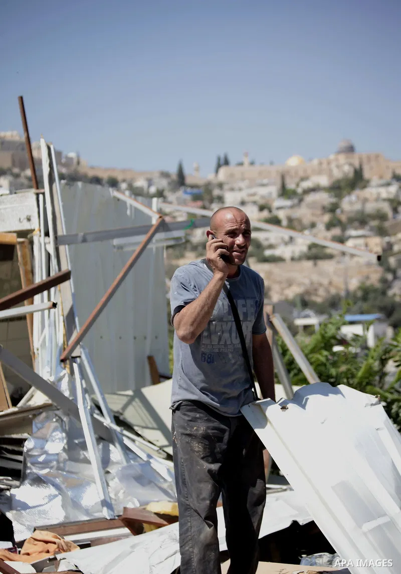 Khaled al-Zeer al-Husaini, 39, speaks on the phone as he searches in the rubble of his house in the east Jerusalem Arab neighbourhood of Silwan, August 26, 2013. Al-Husaini is a father of five children live in a cave, wh...