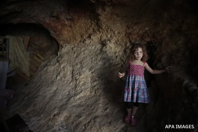 The daughter of Khaled al-Zeer al-Husaini, 39, stands at her father's cave in the east Jerusalem Arab neighbourhood of Silwan, August 26, 2013. Al-Husaini is a father of five children live in a cave, which was a stable f...