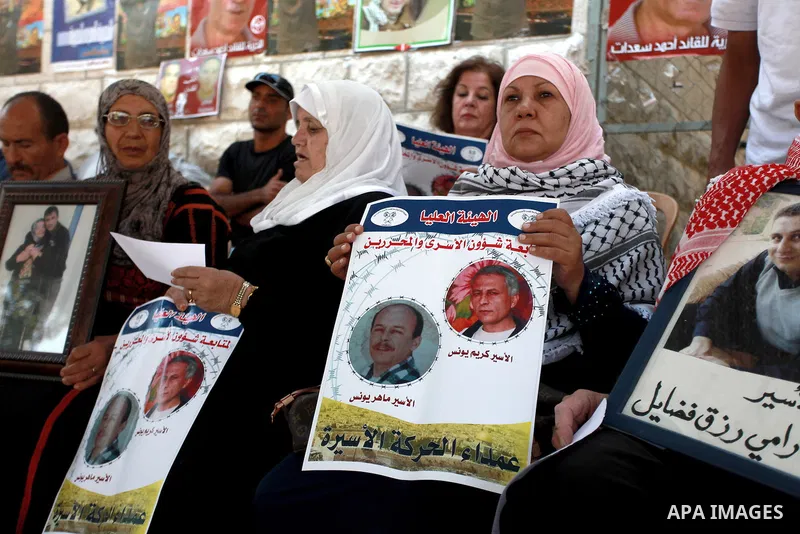 Palestinians hold pictures of prisoners held in Israeli jails during a sit-in outside the Red Crescent offices near the West Bank city of Ramallah on August 27, 2013. Photo by Issam Rimawi
