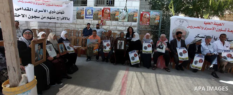 Palestinians hold pictures of prisoners held in Israeli jails during a sit-in outside the Red Crescent offices near the West Bank city of Ramallah on August 27, 2013. Photo by Issam Rimawi