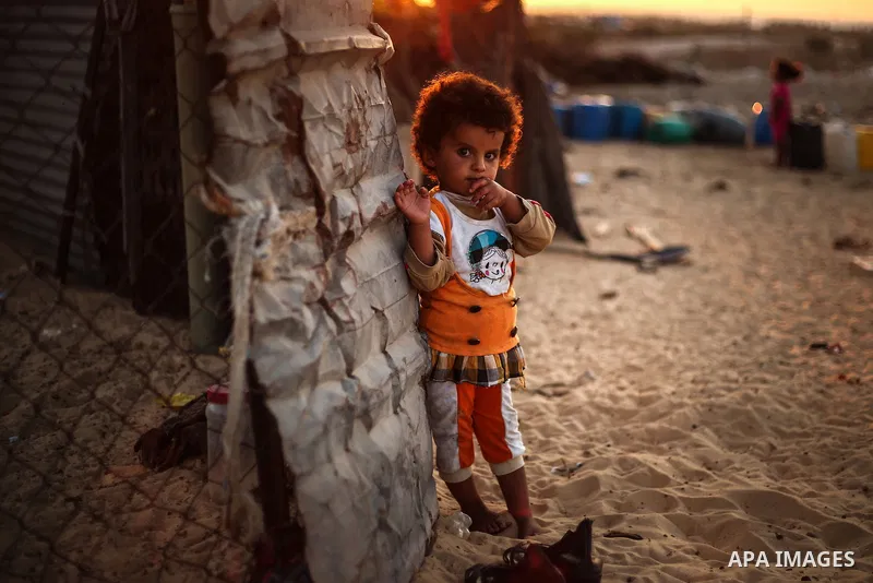 A Palestinian girl poses for a photograph outside her family's tent in a poverty-stricken quarter of the town of Khan Younis, in the southern Gaza Strip, 27 August 2013. Photo by Mahmoud Hamda