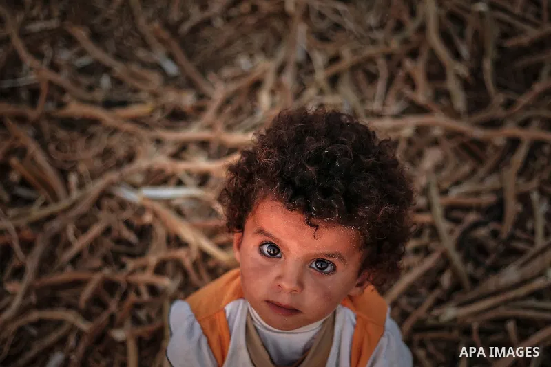 A Palestinian girl poses for a photograph outside her family's tent in a poverty-stricken quarter of the town of Khan Younis, in the southern Gaza Strip, 27 August 2013. Photo by Mahmoud Hamda