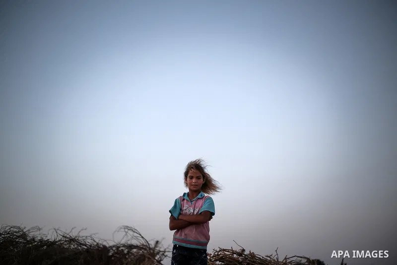 A Palestinian girl poses for a photograph outside her family's tent in a poverty-stricken quarter of the town of Khan Younis, in the southern Gaza Strip, 27 August 2013. Photo by Mahmoud Hamda