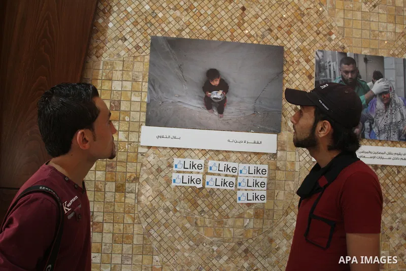 Palestinians attend the photo gallery of Gazans photographers organized by the International Committee of the Red Cross, marking the World Humanitarian Day, in Gaza City on Aug 29, 2013. Photo by Mohammed Asad