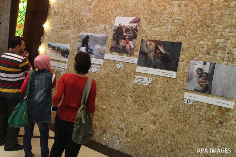 Palestinians attend the photo gallery of Gazans photographers organized by the International Committee of the Red Cross, marking the World Humanitarian Day, in Gaza City on Aug 29, 2013. Photo by Mohammed Asad