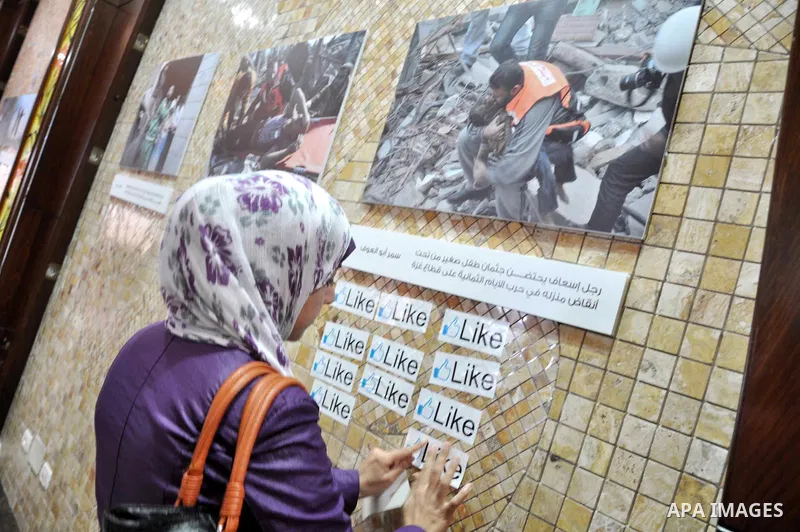 A Palestinian girl attends the photo gallery of Gazans photographers organized by the International Committee of the Red Cross, marking the World Humanitarian Day, in Gaza City on Aug 29, 2013. Photo by Mohammed Talatene