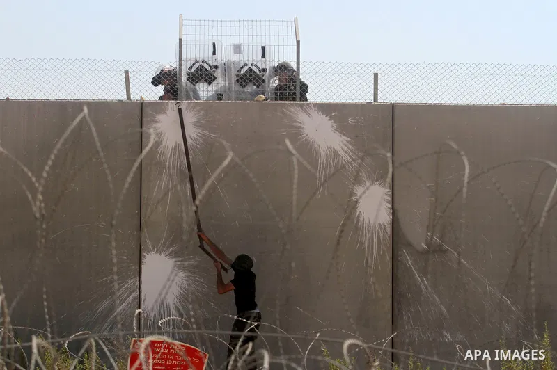 A Palestinian protester uses a metal rod at the controversial Israeli barrier during clashes with Israeli border policemen after a protest against Israel's separation barrier and in solidarity with Palestinian prisoners...