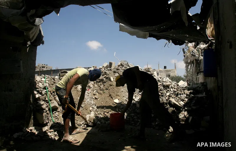 Palestinian laborers work on a crusher machine at a brick factory in Rafah in southern Gaza Strip, Aug 31, 2013. Palestinians re-use old bricks in construction after the Egyptian army started to knock down Gaza smuggling...