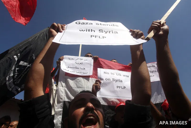 Palestinians hold banners and wave the Syrian flag as they take part in a rally, organized by the Palestinian leftist party, the Popular Front for the Liberation of Palestine (PFLP), against US military action on Syria,...