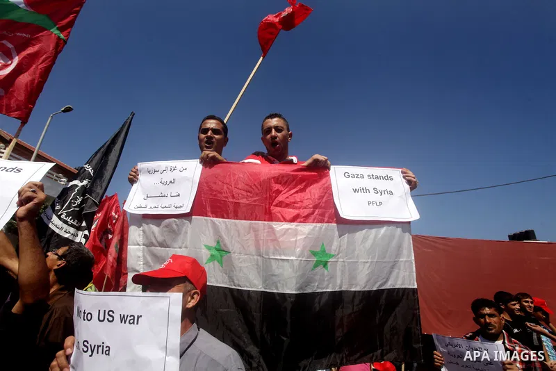 Palestinians hold banners and wave the Syrian flag as they take part in a rally, organized by the Palestinian leftist party, the Popular Front for the Liberation of Palestine (PFLP), against US military action on Syria,...