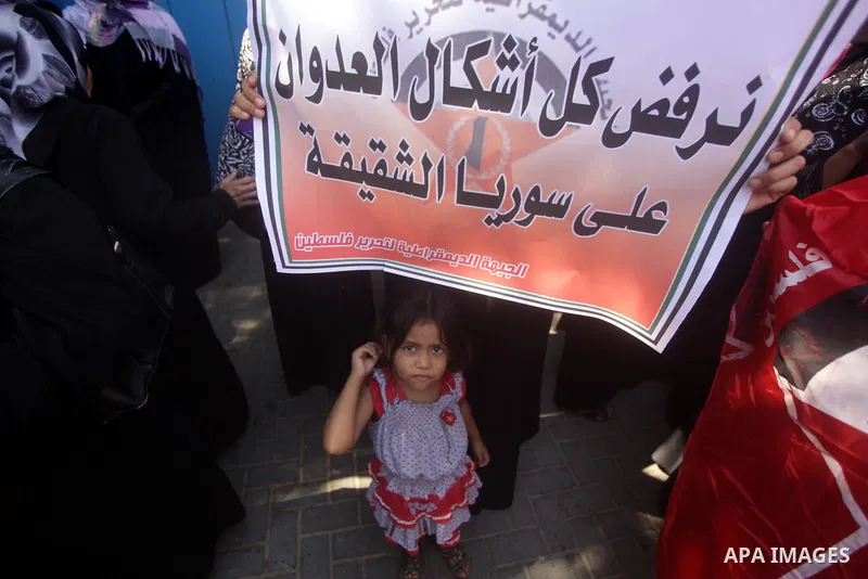 Palestinians hold banners and wave the Syrian flag as they take part in a rally, organized by the Palestinian leftist party, the Popular Front for the Liberation of Palestine (PFLP), against US military action on Syria,...