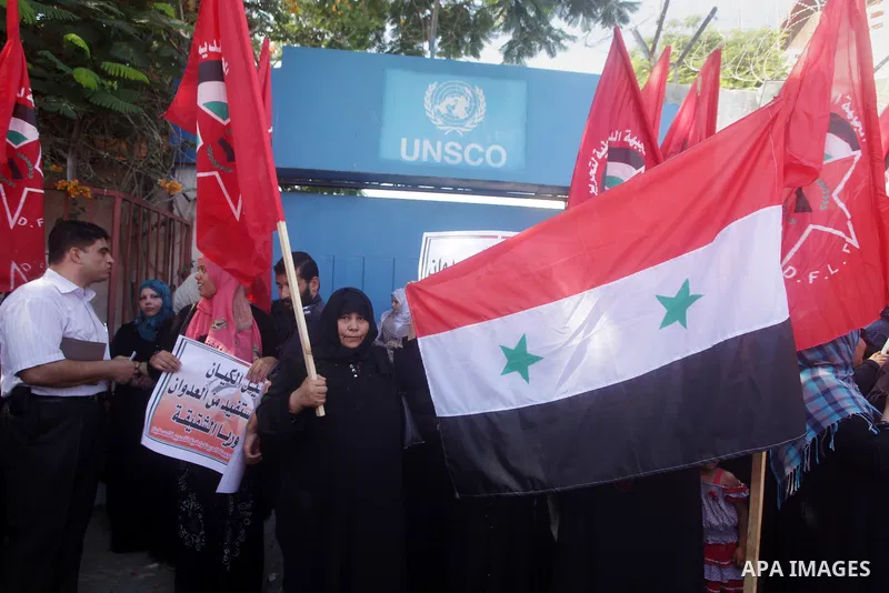 Palestinians hold banners and wave the Syrian flag as they take part in a rally, organized by the Palestinian leftist party, the Popular Front for the Liberation of Palestine (PFLP), against US military action on Syria,...