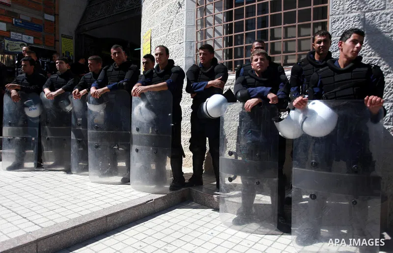 Palestinian policemen stand guard outside the Qatar-based Al-Jazeera Arabic news channel offices where members of the Fatah movement protest following the airing last night of a program they believe insulated the late Pa...
