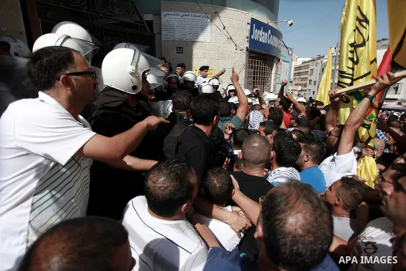 Members of the Fatah movement protest outside the Qatar-based Al-Jazeera Arabic news channel offices as police stand guard following the airing last week of a program they believe insulated the late Palestinian president...