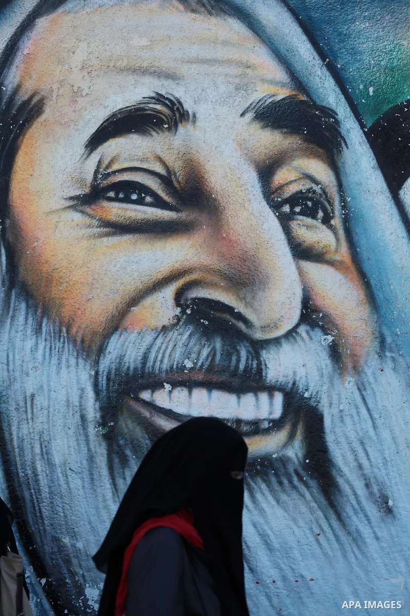A Palestinian student walks past a mural depicting late Palestinian leader Yasser Arafat and late Hamas spiritual leader Ahmed Yassin in Gaza City September 125, 2013. Photo by Ashraf Amra