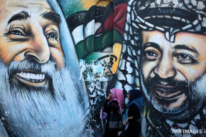 Palestinian students walk past a mural depicting late Palestinian leader Yasser Arafat and late Hamas spiritual leader Ahmed Yassin in Gaza City September 125, 2013. Photo by Ashraf Amra