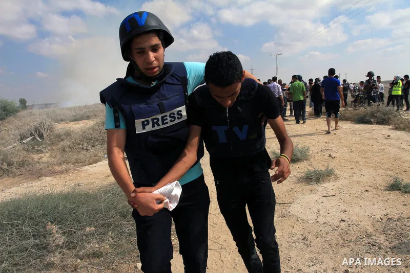 Palestinians help a wounded cameraman after Israeli troops fired tear gas canisters during clashes following a protest in solidarity with Al-Aqsa mosque near the border with Israel, east of Gaza Strip September 27, 2013....