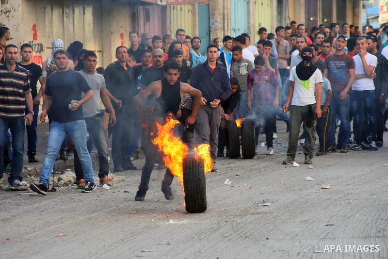 A Palestinian protester kicks a burned tire towards Israeli security forces during clashes in the West Bank city of Hebron September 27, 2013. Israeli police clashed with Palestinian protesters in Jerusalem's Old City, t...