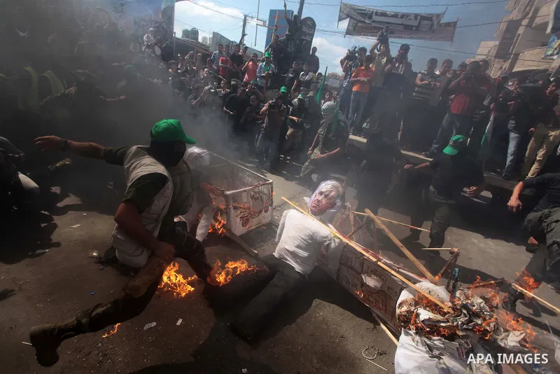 Palestinian Hamas supporters burn a mock coffin covered with an Israeli flag and effigies of Israeli President Shimon Peres during a protest to show solidarity with Al-Aqsa mosque after Friday prayers in the central Gaza...