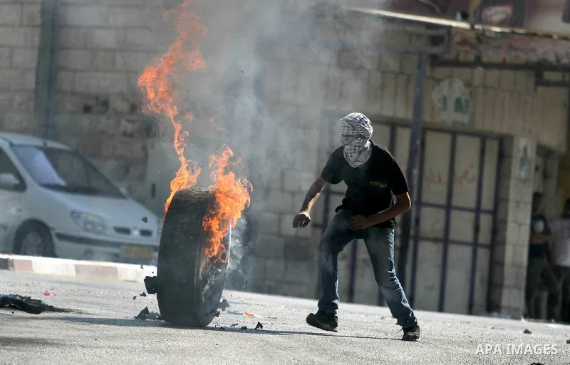 A Palestinian stands next to burning tires during clashes with Israeli soldiers in north of Jerusalem city on September 27, 2013. Thousands of Palestinians demonstrated in the Gaza Strip, the West Bank and east Jerusalem...
