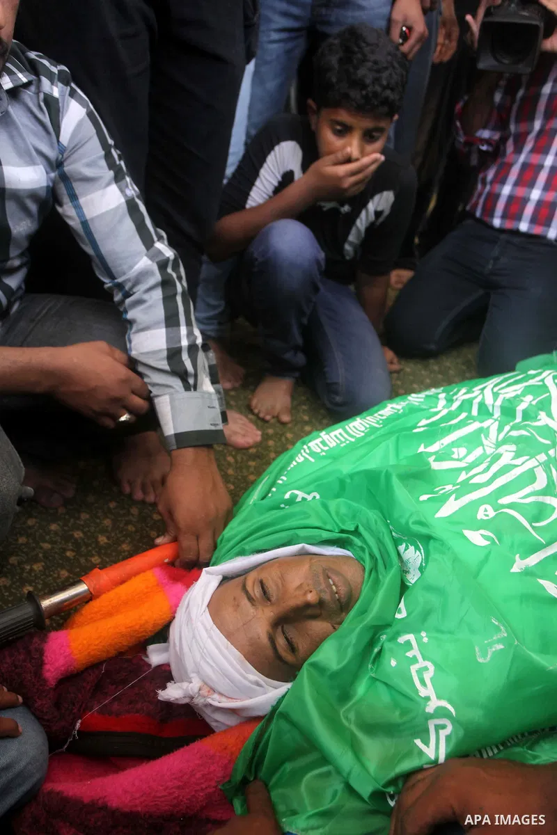 Palestinians sit next to the body of Palestinian Heweshil Abu Heweshil, who was killed by Israeli soldiers, during his funeral in center Gaza City October 1, 2013. Israeli soldiers shot dead Abu Heweshil near the border...