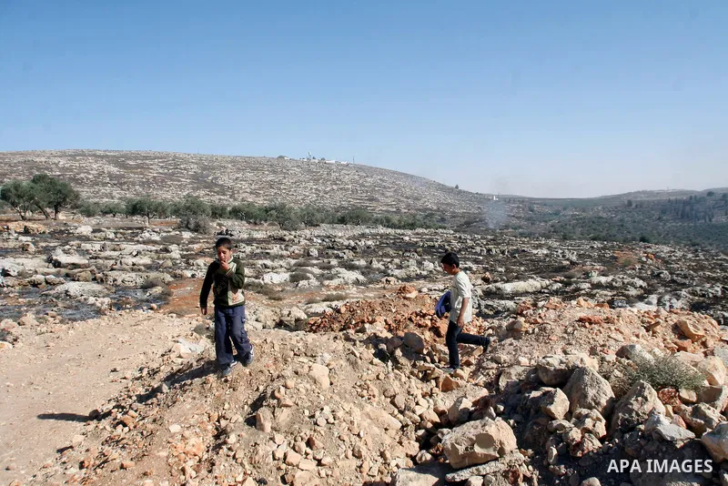 Palestinian children look as smoke rises from the agricultural land near the West Bank village of Jalud southern Nablus on October 09, 2013. Dozens of settlers from the nearby settlement of Esh Kodesh set fire to agricul...