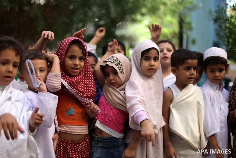 Palestinian children gather around a makeshift cube representing the holy Kaaba in Gaza city, on October 12, 2013, as part of training children how to perform Hajj pilgrimage. Muslims from around the world flood Saudi ci...