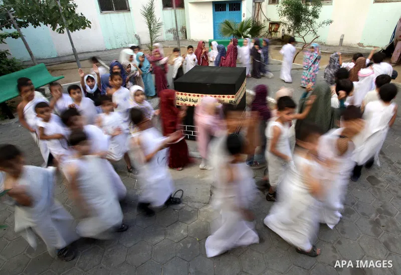 Palestinian children gather around a makeshift cube representing the holy Kaaba in Gaza city, on October 12, 2013, as part of training children how to perform Hajj pilgrimage. Muslims from around the world flood Saudi ci...