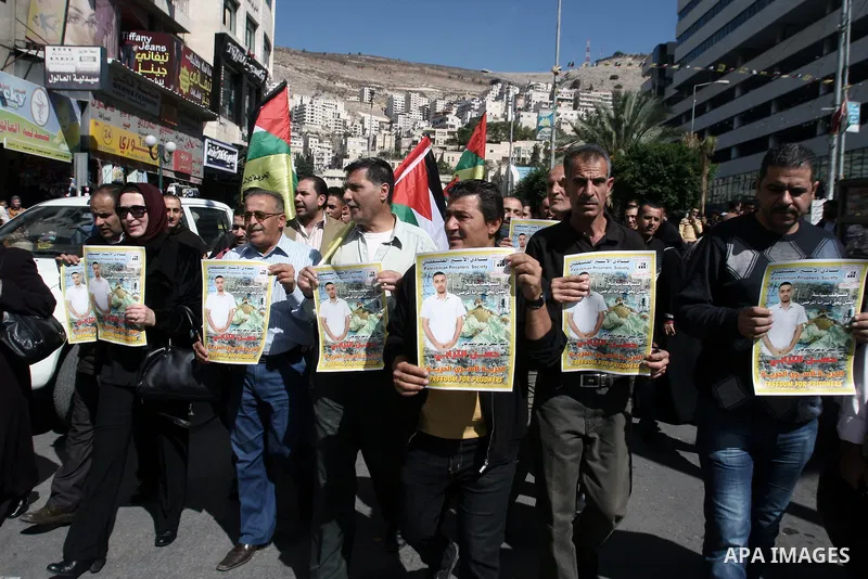 Protesters hold portraits of Hassan al-Turabi, a Palestinian prisoner, during a demonstration in solidarity with prisoners in Israeli jails, in the West Bank City of Nablus, Oct. 20, 2013. The Palestinian Prisoners' Soci...