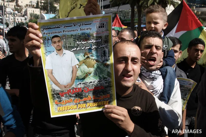 Protesters hold portraits of Hassan al-Turabi, a Palestinian prisoner, during a demonstration in solidarity with prisoners in Israeli jails, in the West Bank City of Nablus, Oct. 20, 2013. The Palestinian Prisoners' Soci...