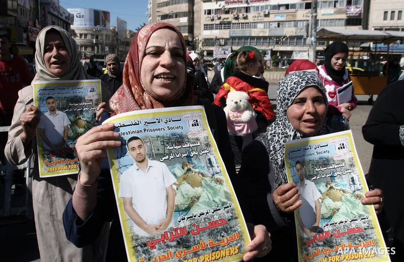 Protesters hold portraits of Hassan al-Turabi, a Palestinian prisoner, during a demonstration in solidarity with prisoners in Israeli jails, in the West Bank City of Nablus, Oct. 20, 2013. The Palestinian Prisoners' Soci...