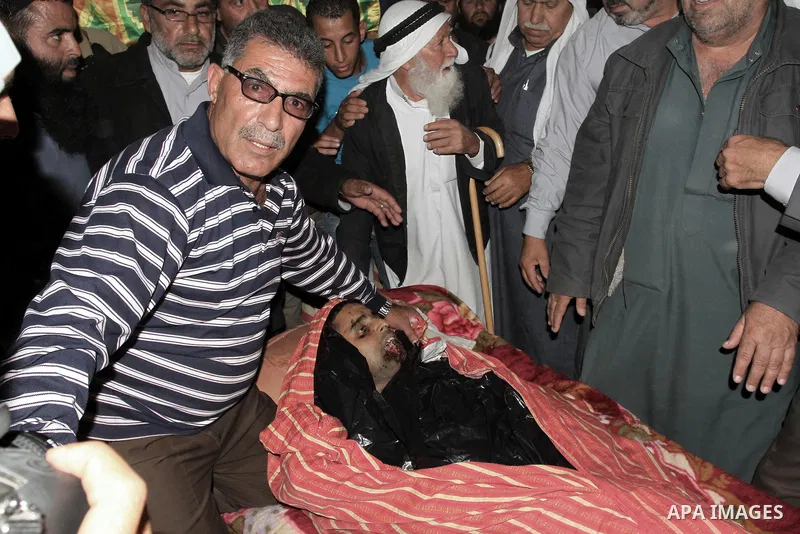 Palestinian relatives of Younis al-Radaideh mourn over his body during his funeral in Ubiedyeh village near the West Bank city of Bethlehem, Oct. 21, 2013. Israeli forces on Thursday shot and killed Younis Ahmed Radaideh...