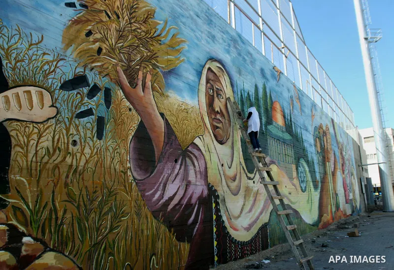 A Palestinian artist paints a mural depicting Palestinian heritage, in the West Bank city of Nablus, on Oct. 24, 2013. Photo by Nedal Eshtayah