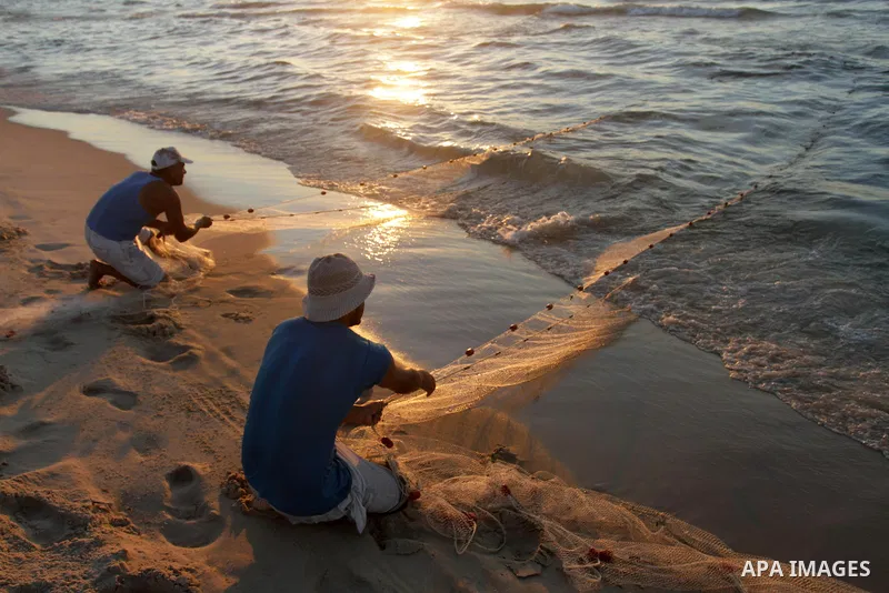 Palestinian fishermen pull their net from the sea during the sunset at the beach of Gaza City, on Oct. 24, 2013. Israel restricted the fishing zone to three nautical miles following the kidnapping of Israeli soldier Gila...