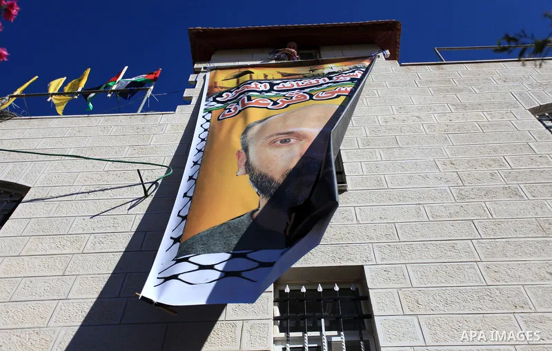 A relative hangs a banner depicting Palestinian prisoner Moses Qar'an outside his house, in the West Bank city of Ramallah October 28, 2013. Qar'an is one of 26 Palestinian prisoners that Israel approved on Sunday to rel...