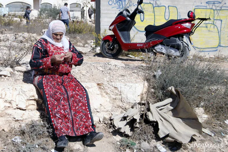 A Palestinian woman sits next to the remains of a house belonging to Palestinians after demolished by Israeli Municipality in the East Jerusalem neighbourhood of Beit Hanina, October 29, 2013. A statement from the Jerusa...