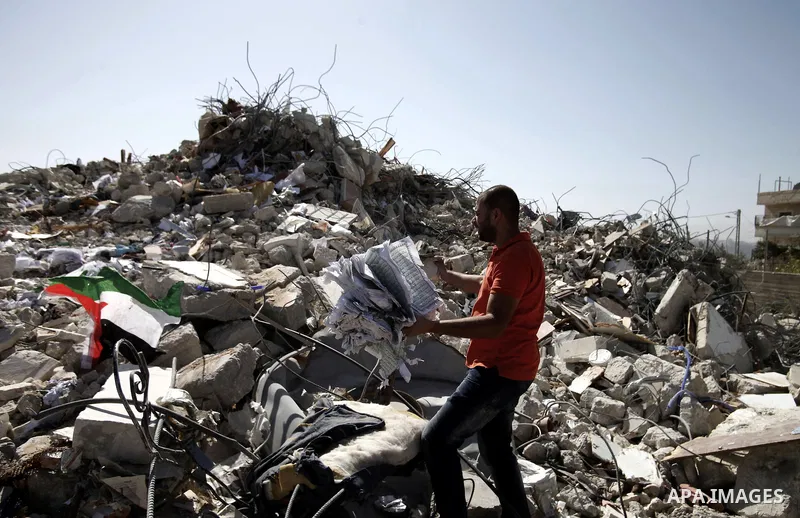 A Palestinian grabs a Koran from the remains of a house, belonging to a Palestinian family after demolished by Israeli Municipality in the East Jerusalem neighbourhood of Beit Hanina, October 29, 2013. A statement from t...