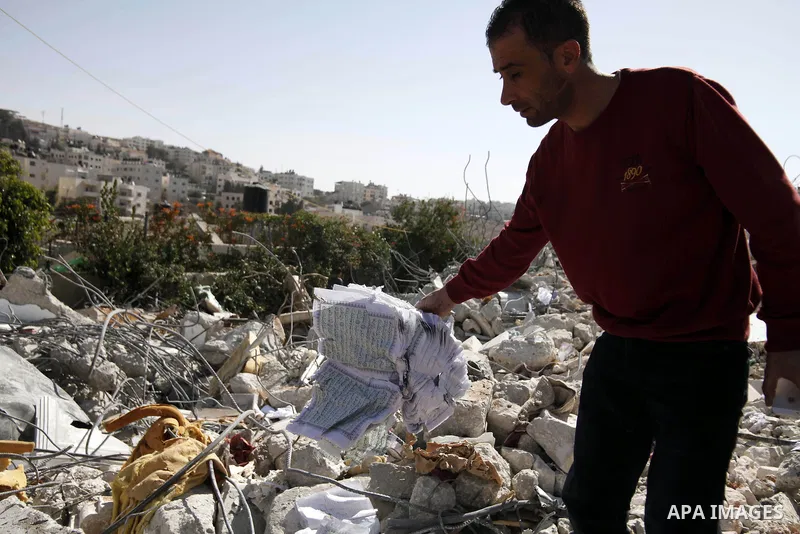 A Palestinian grabs a Koran from the remains of a house, belonging to a Palestinian family after demolished by Israeli Municipality in the East Jerusalem neighbourhood of Beit Hanina, October 29, 2013. A statement from t...