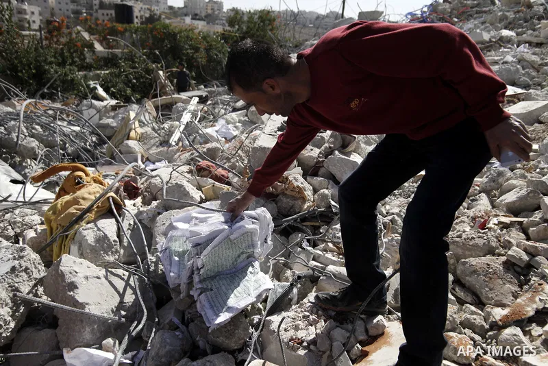 A Palestinian grabs a Koran from the remains of a house, belonging to a Palestinian family after demolished by Israeli Municipality in the East Jerusalem neighbourhood of Beit Hanina, October 29, 2013. A statement from t...