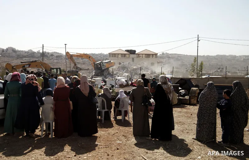 Palestinian women watch during demolishing of a house belonging to Palestinians is being demolished by Israeli municipality in the East Jerusalem neighbourhood of Beit Hanina, October 29, 2013. A statement from the Jerus...