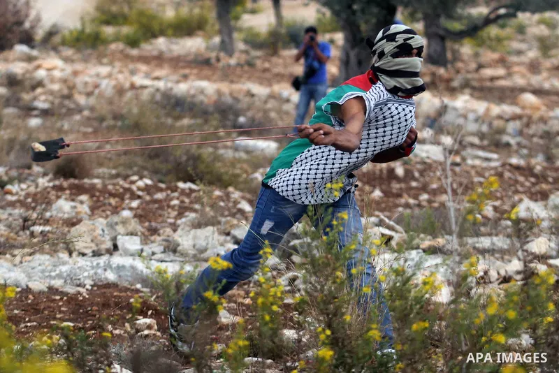 A Palestinian protester hurls stones towards Israeli security forces during clashes after a demonstration against Israel's separation barrier and in solidarity with Palestinian prisoners being held in Israeli jails, in t...