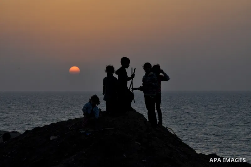 Palestinian children play outside their house during sunset at Al-Shatea' refugee camp in Gaza City on November 8, 2013. Gaza's lone power plant shut its generators on Friday due to a fuel shortage, a move that will like...