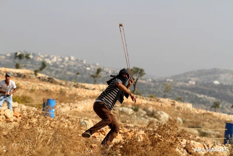 Palestinian protesters throw stones towards Israeli security forces (unseen) in the West Bank village of Bilin, West of Ramallah, on November 15, 2013, following a march to mark the 25th anniversary of the Palestinian In...