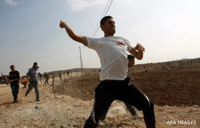 A Palestinian youth throws stones at Israeli army jeeps during clashes following a confrontation between Palestinians and Jewish settlers, in the West Bank village of Qusra, near Nablus, November 18, 2013. Jewish settler...