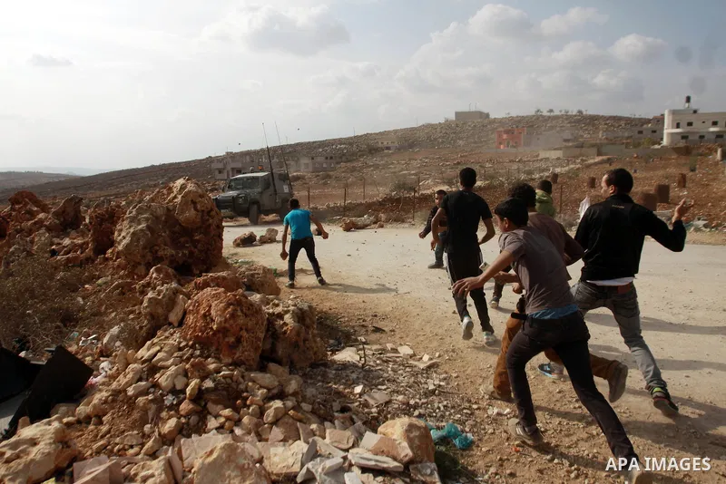 Palestinian youths throw stones at Israeli army jeeps during clashes following a confrontation between Palestinians and Jewish settlers, in the West Bank village of Qusra, near Nablus, November 18, 2013. Jewish settlers...