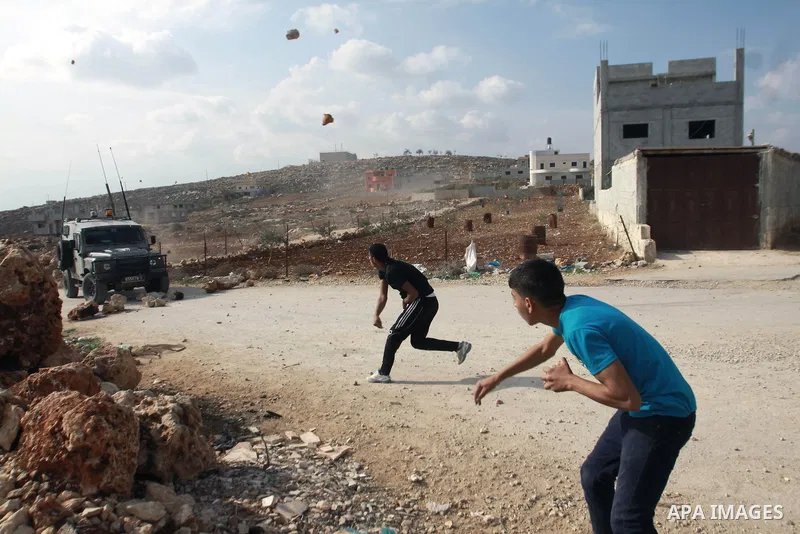 Palestinian youths throw stones at Israeli army jeeps during clashes following a confrontation between Palestinians and Jewish settlers, in the West Bank village of Qusra, near Nablus, November 18, 2013. Jewish settlers...
