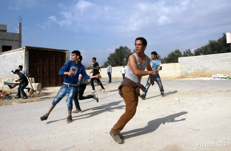 Palestinian youths throw stones at Israeli army jeeps during clashes following a confrontation between Palestinians and Jewish settlers, in the West Bank village of Qusra, near Nablus, November 18, 2013. Jewish settlers...